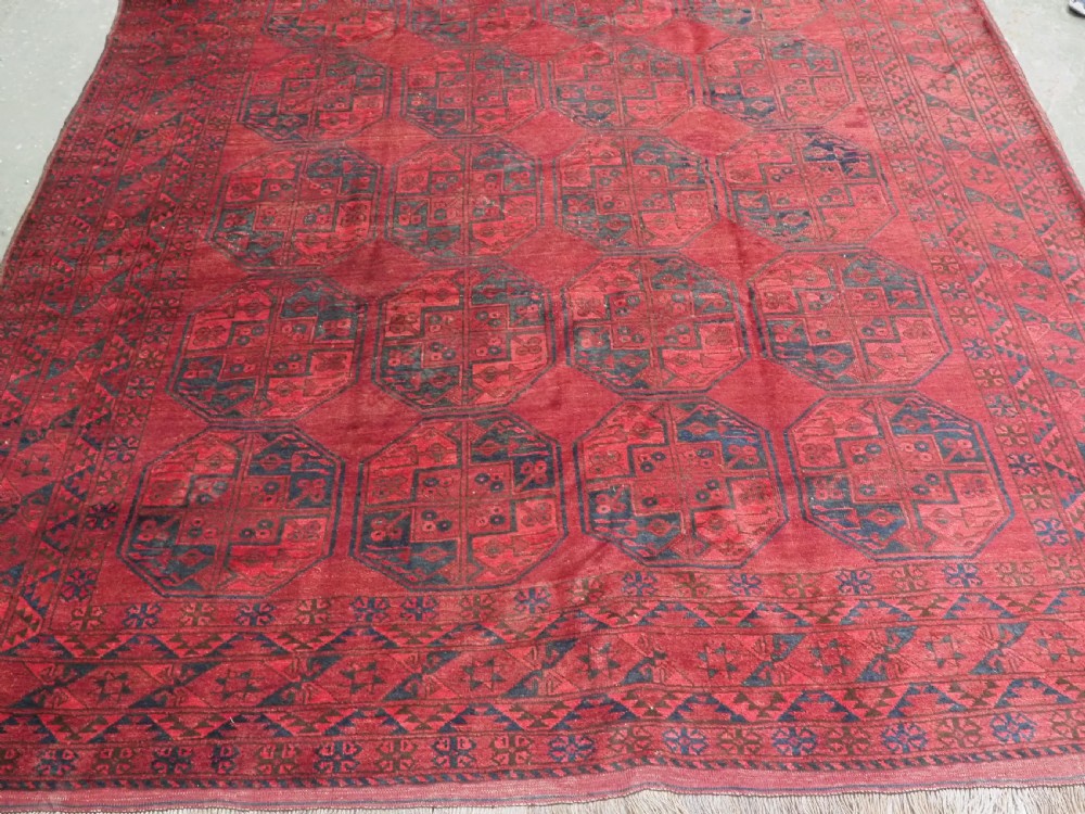 A large antique hand-knotted Afghan Ersari wool carpet featuring repeating octagonal gul patterns on a deep red field. View V