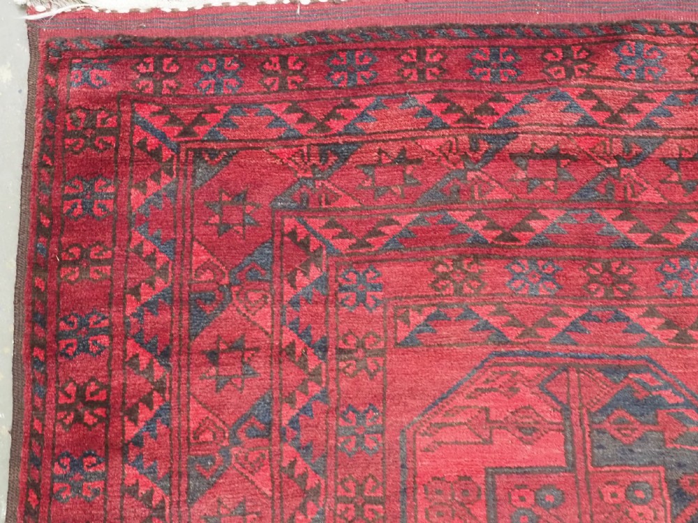 A large antique hand-knotted Afghan Ersari wool carpet featuring repeating octagonal gul patterns on a deep red field. View VI