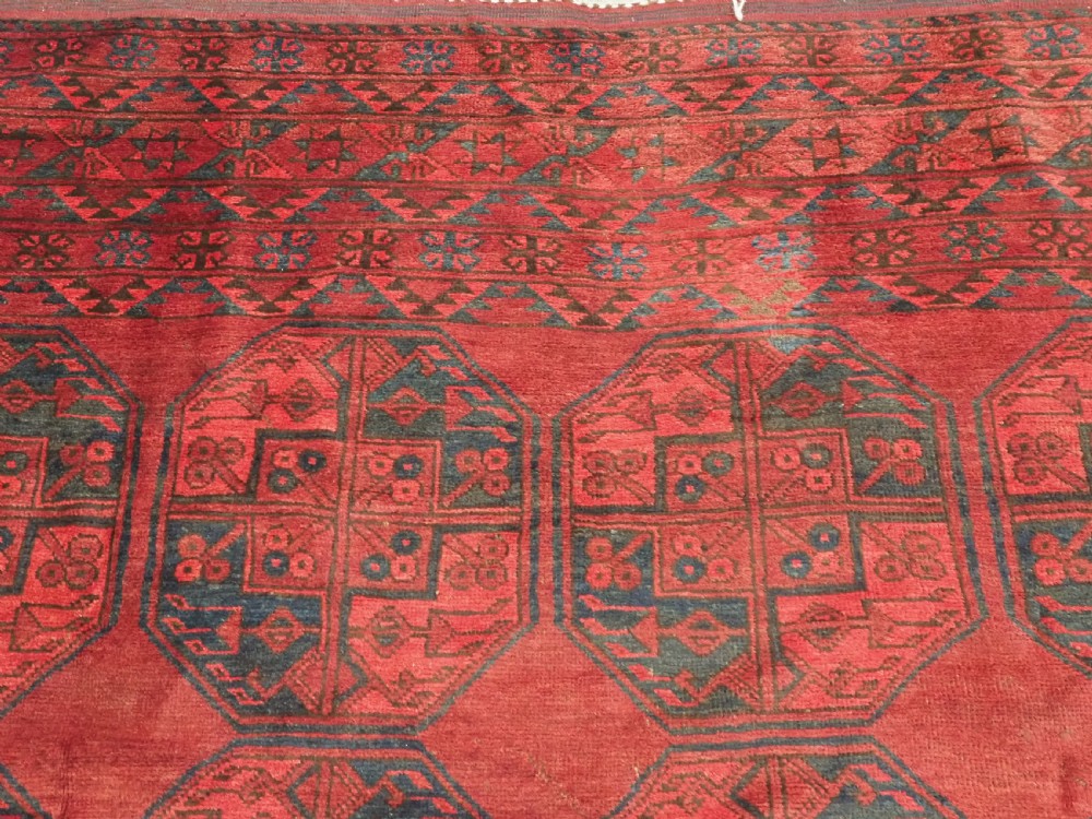 A large antique hand-knotted Afghan Ersari wool carpet featuring repeating octagonal gul patterns on a deep red field. View VIII