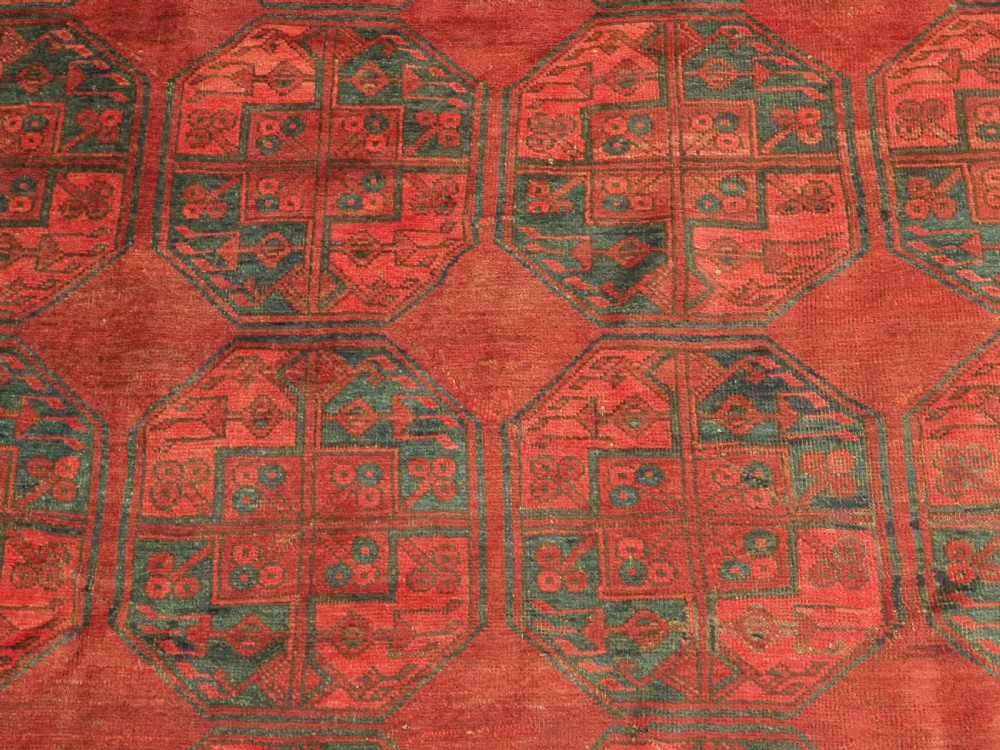 A large antique hand-knotted Afghan Ersari wool carpet featuring repeating octagonal gul patterns on a deep red field. View IX