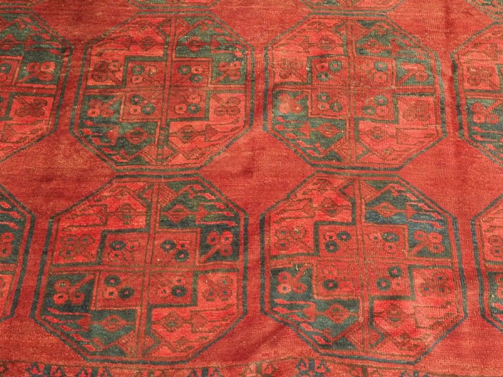 A large antique hand-knotted Afghan Ersari wool carpet featuring repeating octagonal gul patterns on a deep red field. View X