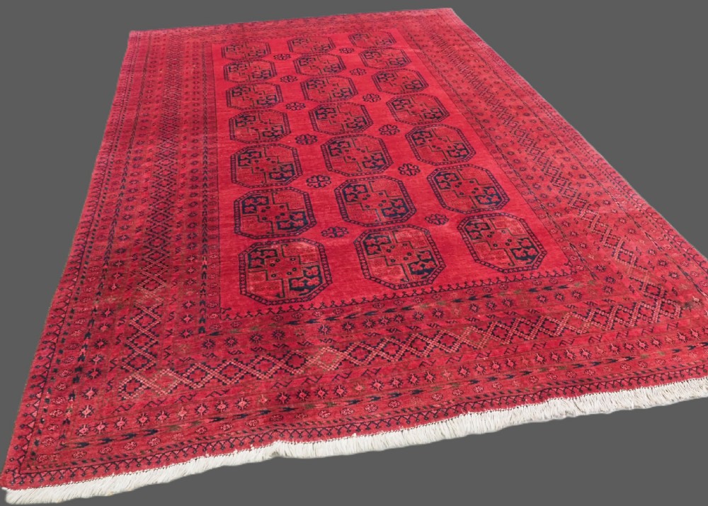 An antique hand-knotted wool carpet featuring repeating octagonal gul motifs on a deep crimson field surrounded by geometric patterned borders. View II
