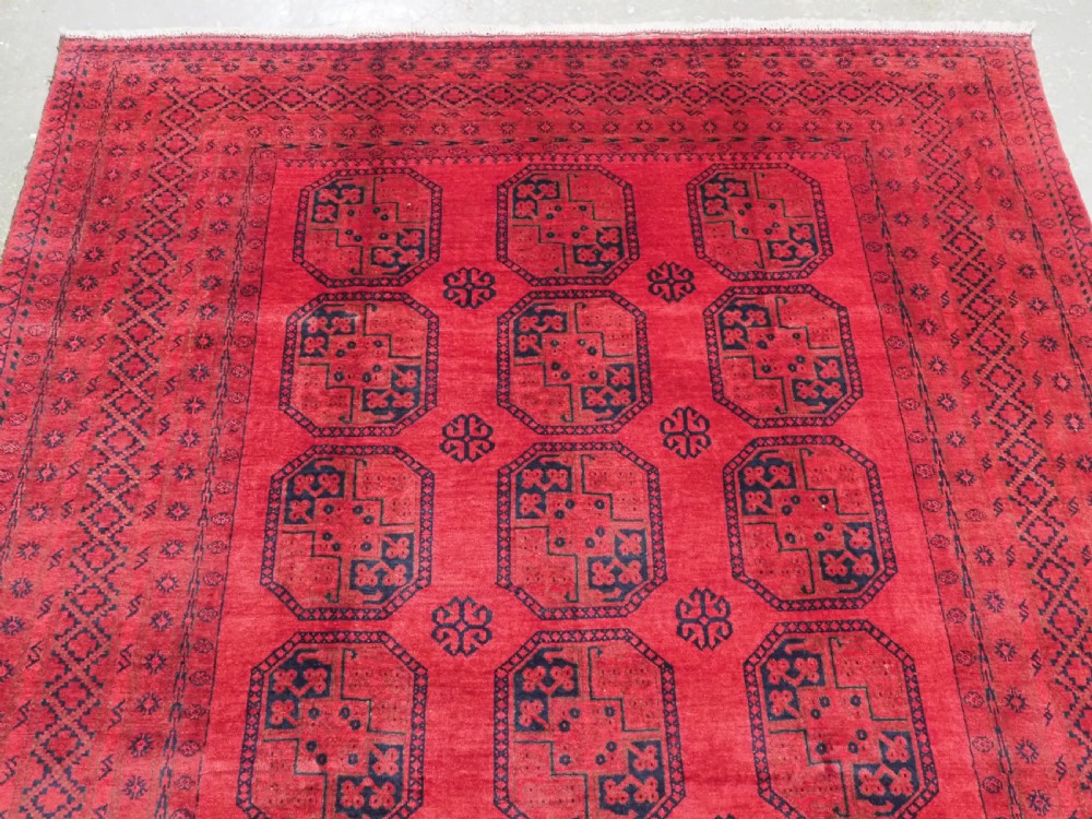 An antique hand-knotted wool carpet featuring repeating octagonal gul motifs on a deep crimson field surrounded by geometric patterned borders. View III