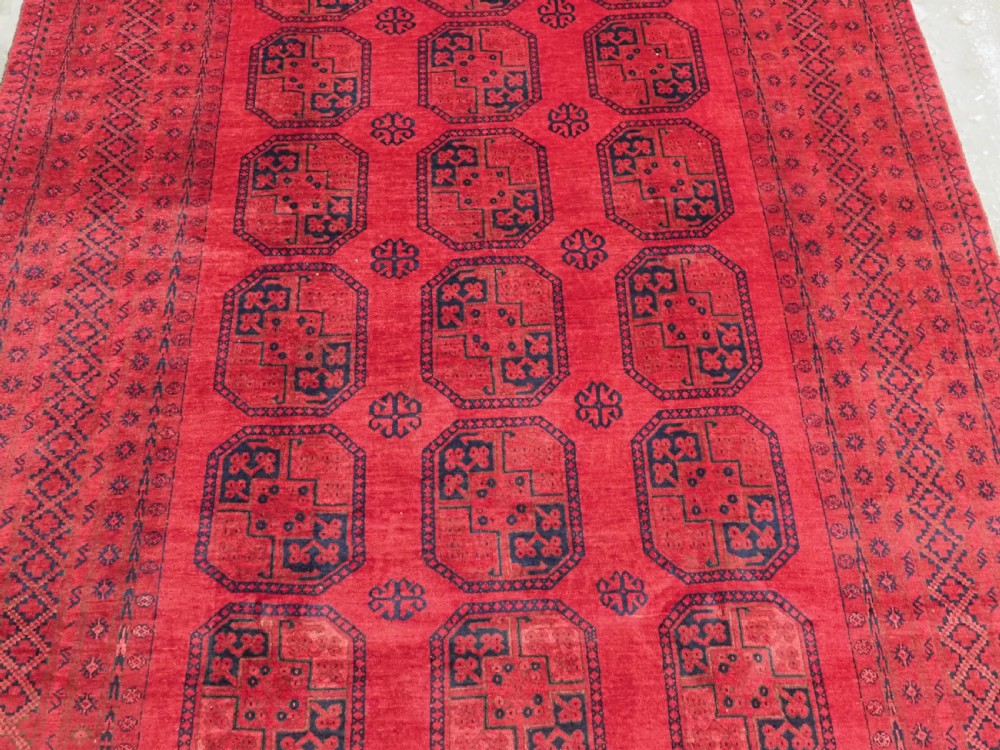 An antique hand-knotted wool carpet featuring repeating octagonal gul motifs on a deep crimson field surrounded by geometric patterned borders. View IV