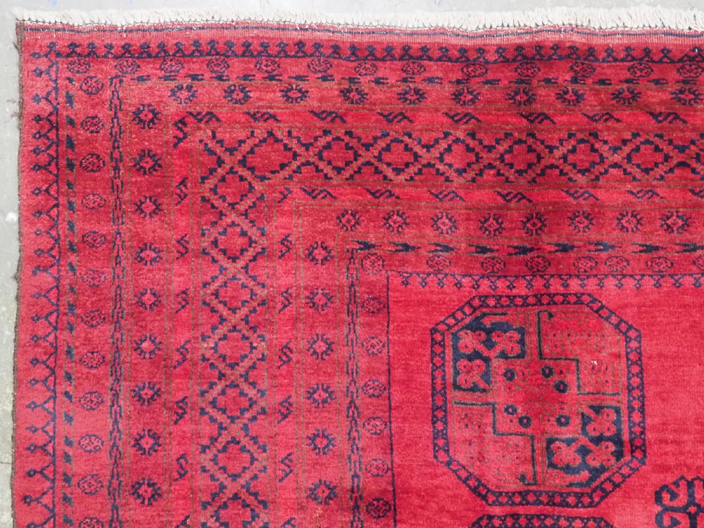 An antique hand-knotted wool carpet featuring repeating octagonal gul motifs on a deep crimson field surrounded by geometric patterned borders. View V
