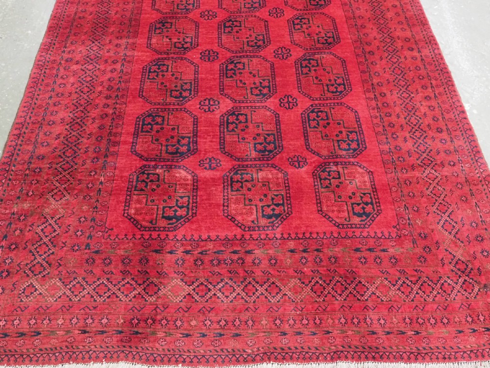 An antique hand-knotted wool carpet featuring repeating octagonal gul motifs on a deep crimson field surrounded by geometric patterned borders. View VI