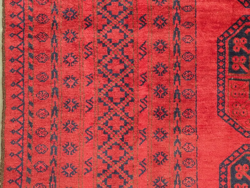 An antique hand-knotted wool carpet featuring repeating octagonal gul motifs on a deep crimson field surrounded by geometric patterned borders. View VII