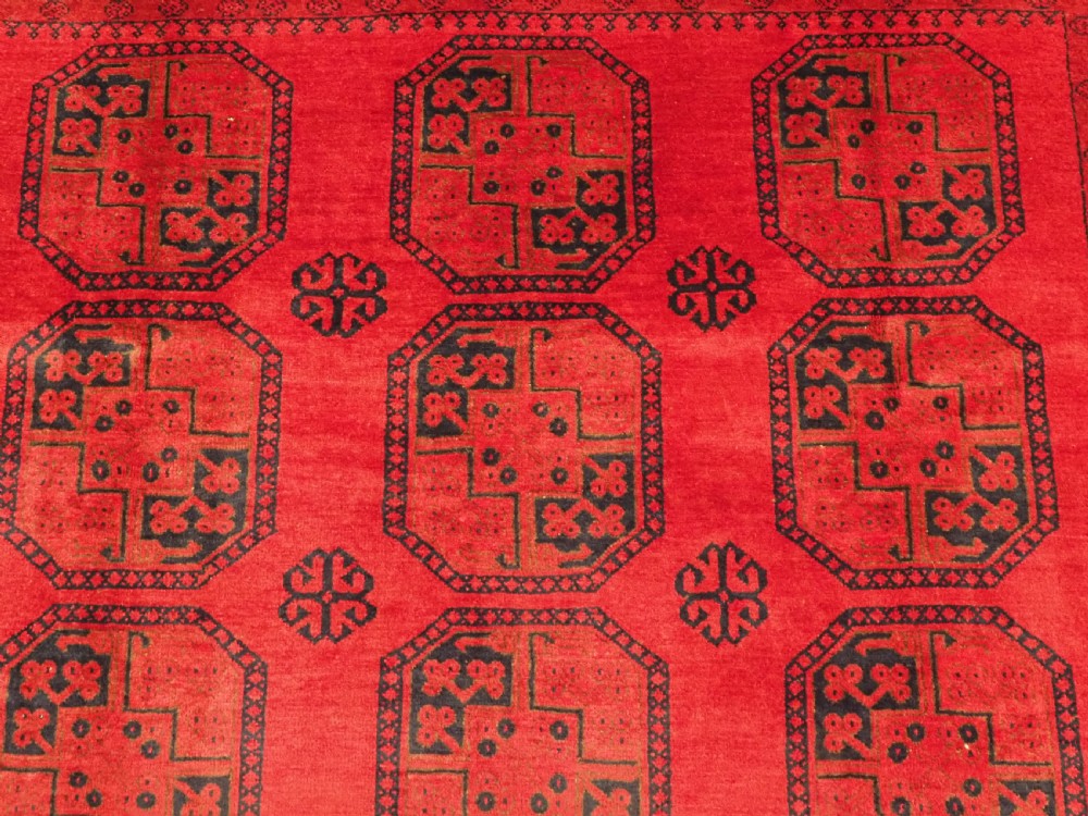 An antique hand-knotted wool carpet featuring repeating octagonal gul motifs on a deep crimson field surrounded by geometric patterned borders. View VIII
