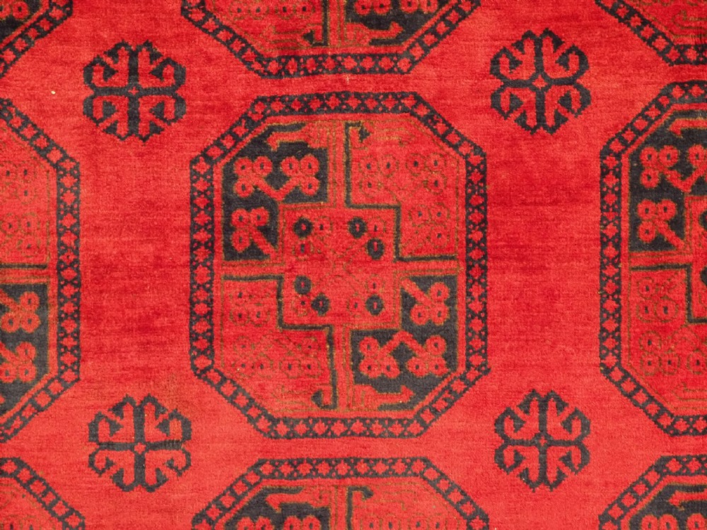An antique hand-knotted wool carpet featuring repeating octagonal gul motifs on a deep crimson field surrounded by geometric patterned borders. View IX