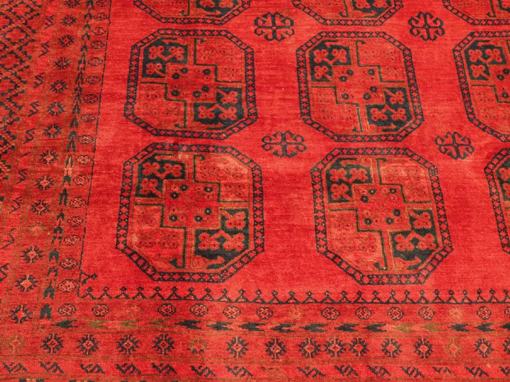 An antique hand-knotted wool carpet featuring repeating octagonal gul motifs on a deep crimson field surrounded by geometric patterned borders. View X