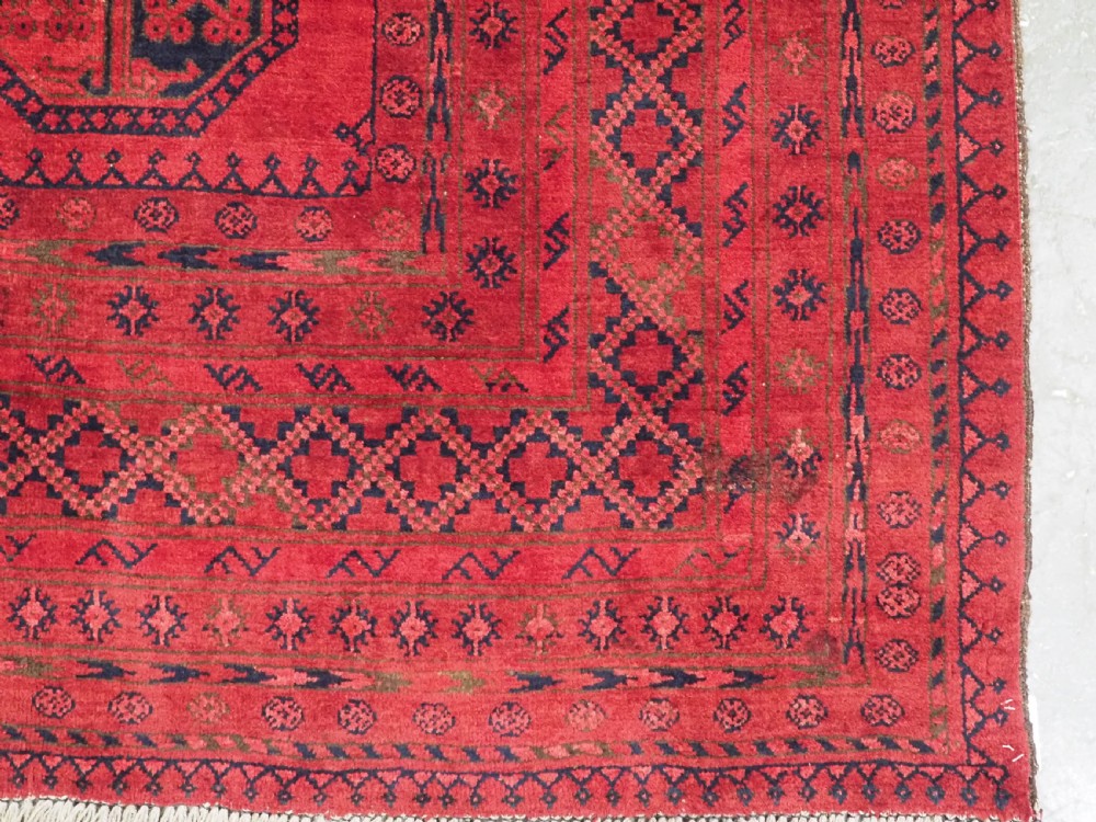 An antique hand-knotted wool carpet featuring repeating octagonal gul motifs on a deep crimson field surrounded by geometric patterned borders. View XI
