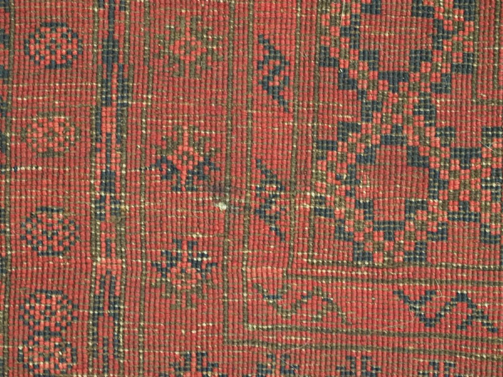 An antique hand-knotted wool carpet featuring repeating octagonal gul motifs on a deep crimson field surrounded by geometric patterned borders. View XII
