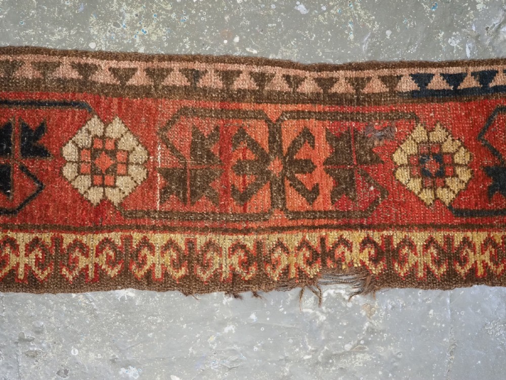 A long, narrow antique Kyrgyz woven wool tegerich fragment featuring geometric star motifs on a deep red background with brown decorative borders. View III