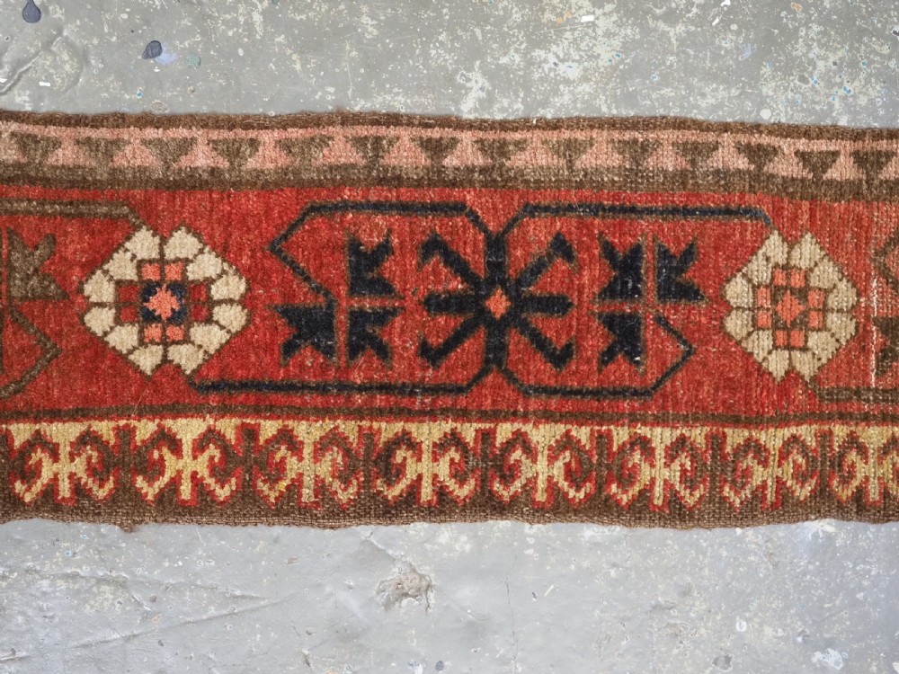 A long, narrow antique Kyrgyz woven wool tegerich fragment featuring geometric star motifs on a deep red background with brown decorative borders. View IV