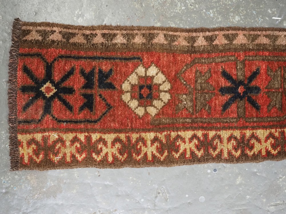 A long, narrow antique Kyrgyz woven wool tegerich fragment featuring geometric star motifs on a deep red background with brown decorative borders. View VI