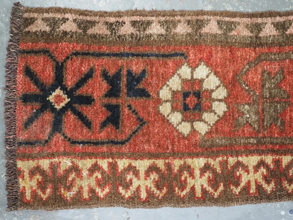 A long, narrow antique Kyrgyz woven wool tegerich fragment featuring geometric star motifs on a deep red background with brown decorative borders. View VII