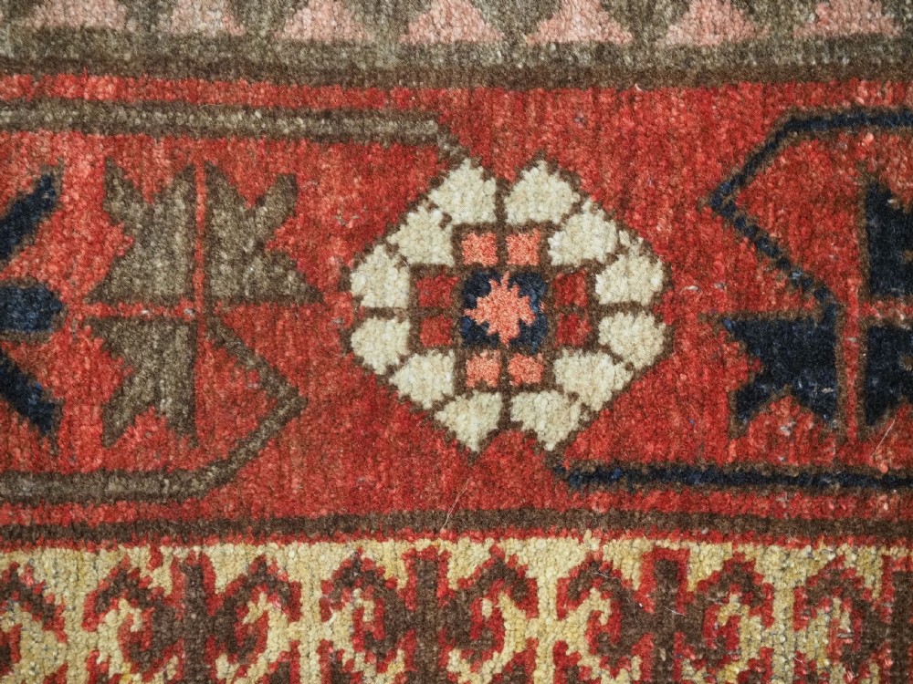 A long, narrow antique Kyrgyz woven wool tegerich fragment featuring geometric star motifs on a deep red background with brown decorative borders. View IX
