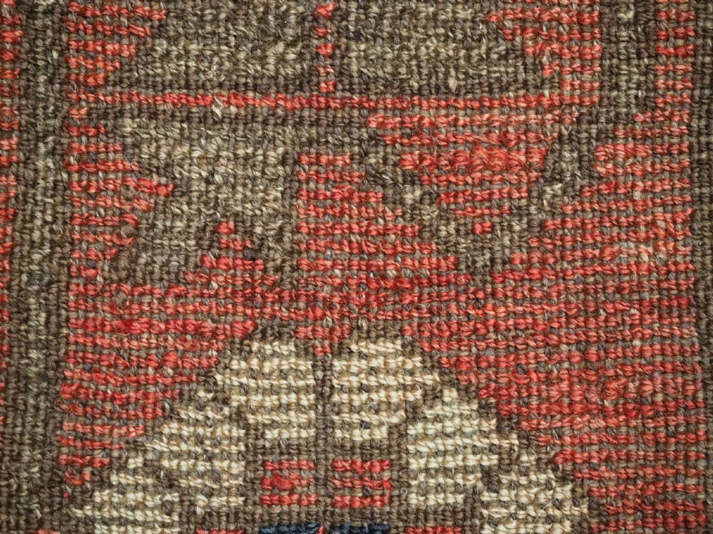 A long, narrow antique Kyrgyz woven wool tegerich fragment featuring geometric star motifs on a deep red background with brown decorative borders. View X