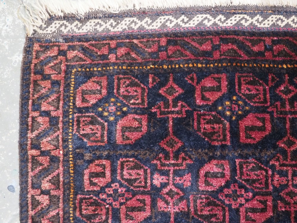 An antique hand-woven Baluch saddle bag face featuring dark red and navy geometric tile patterns with flatwoven web borders. View II