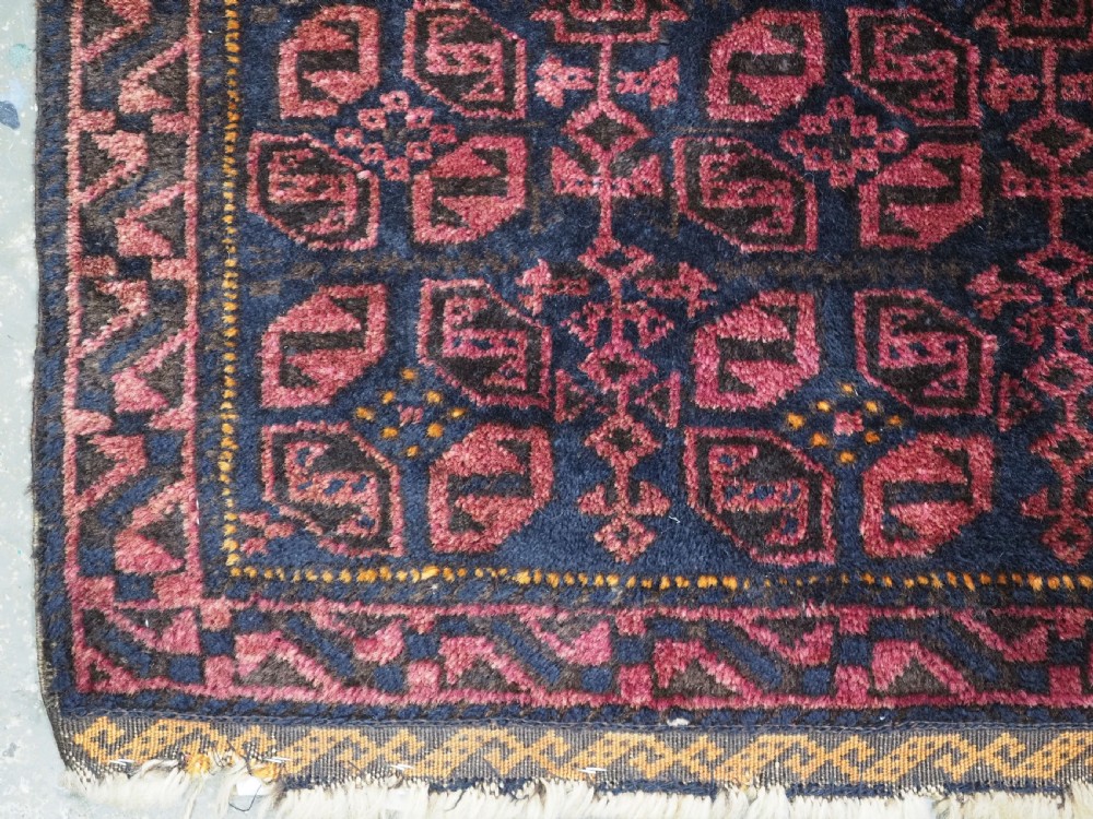 An antique hand-woven Baluch saddle bag face featuring dark red and navy geometric tile patterns with flatwoven web borders. View III
