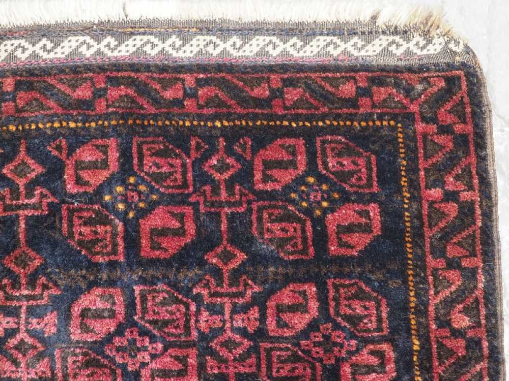 An antique hand-woven Baluch saddle bag face featuring dark red and navy geometric tile patterns with flatwoven web borders. View IV