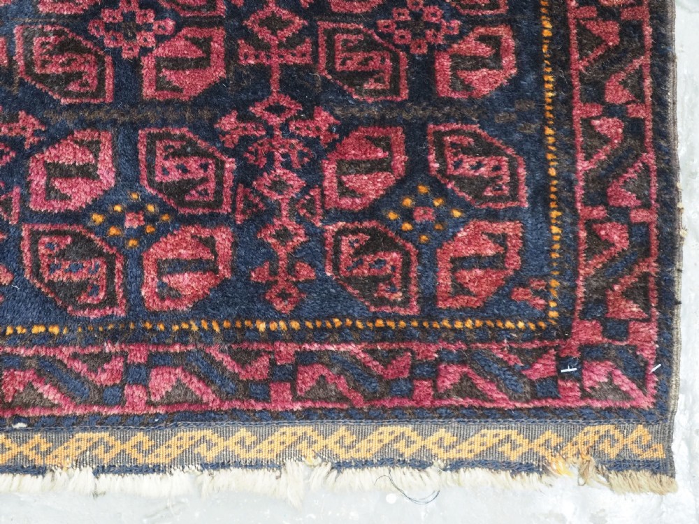 An antique hand-woven Baluch saddle bag face featuring dark red and navy geometric tile patterns with flatwoven web borders. View V