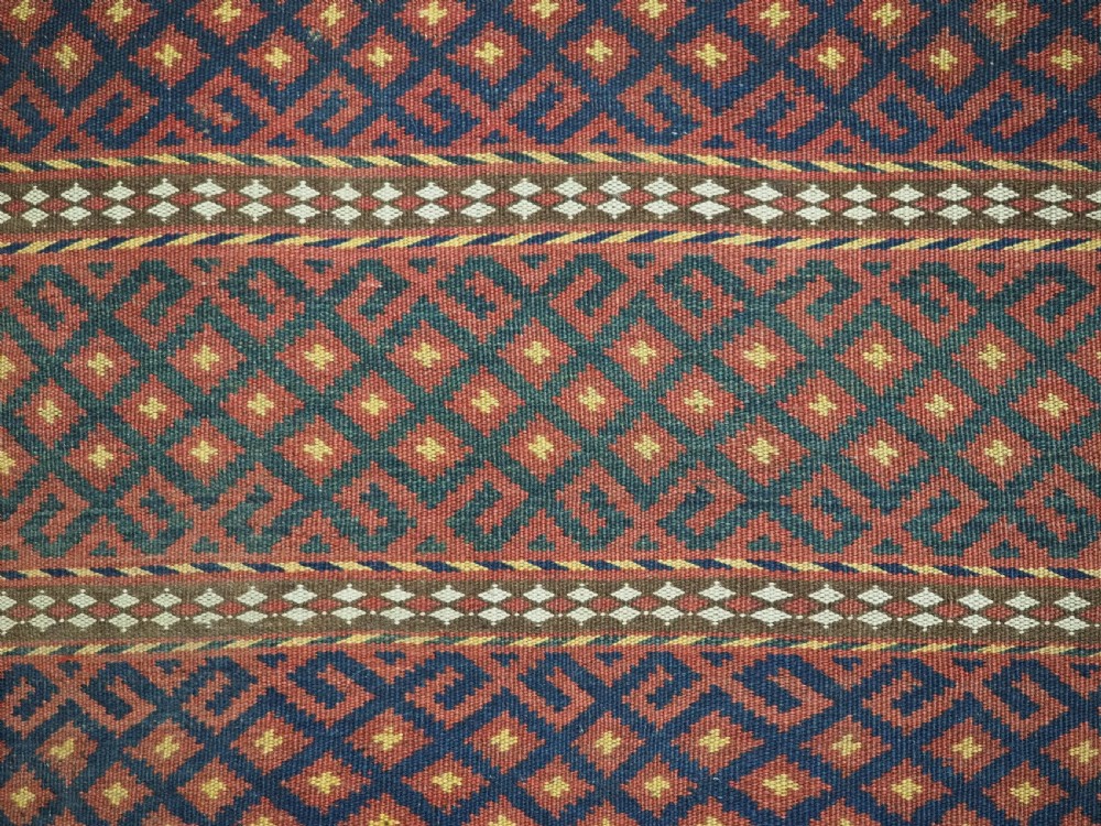 A square handwoven wool Uzbek saddlebag face displaying red and navy blue geometric diamond lattice patterns between banded horizontal stripes. View VIII