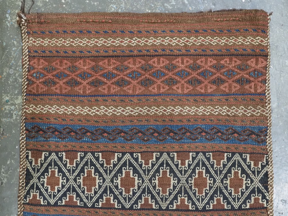 An antique woven Baluch storage bag featuring horizontal bands of geometric diamond motifs in terracotta, indigo blue, and cream wool. View II