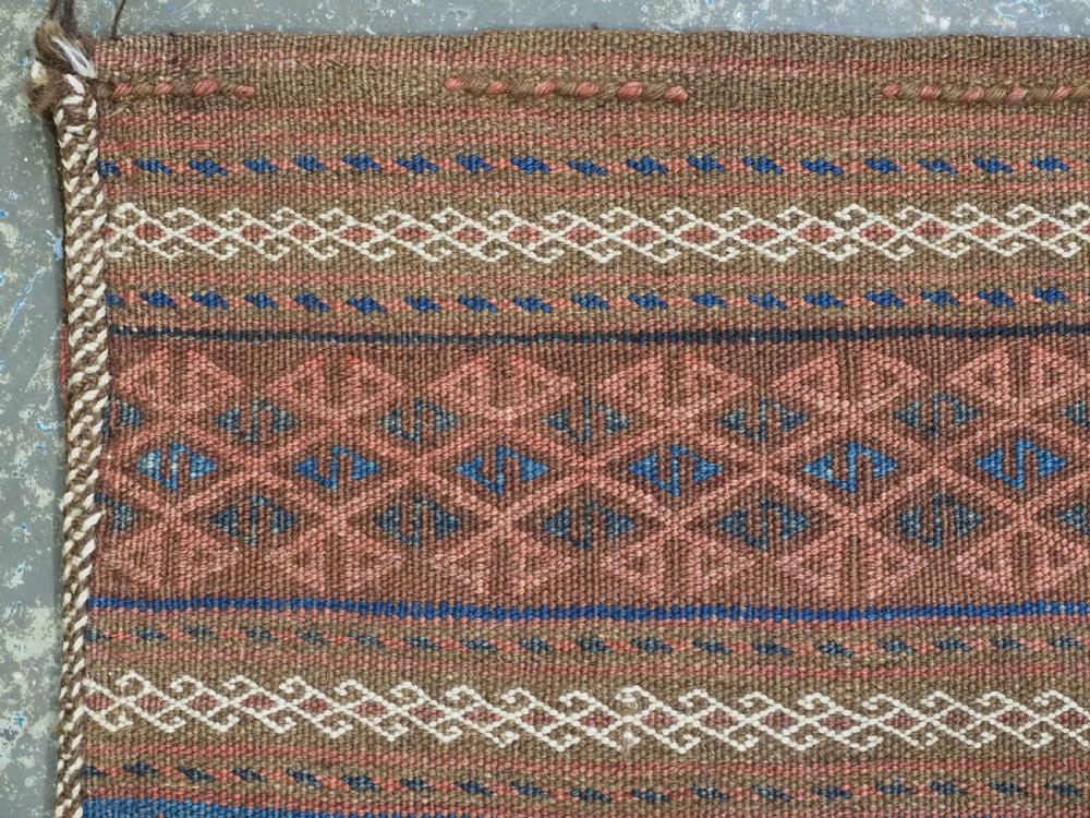An antique woven Baluch storage bag featuring horizontal bands of geometric diamond motifs in terracotta, indigo blue, and cream wool. View IV