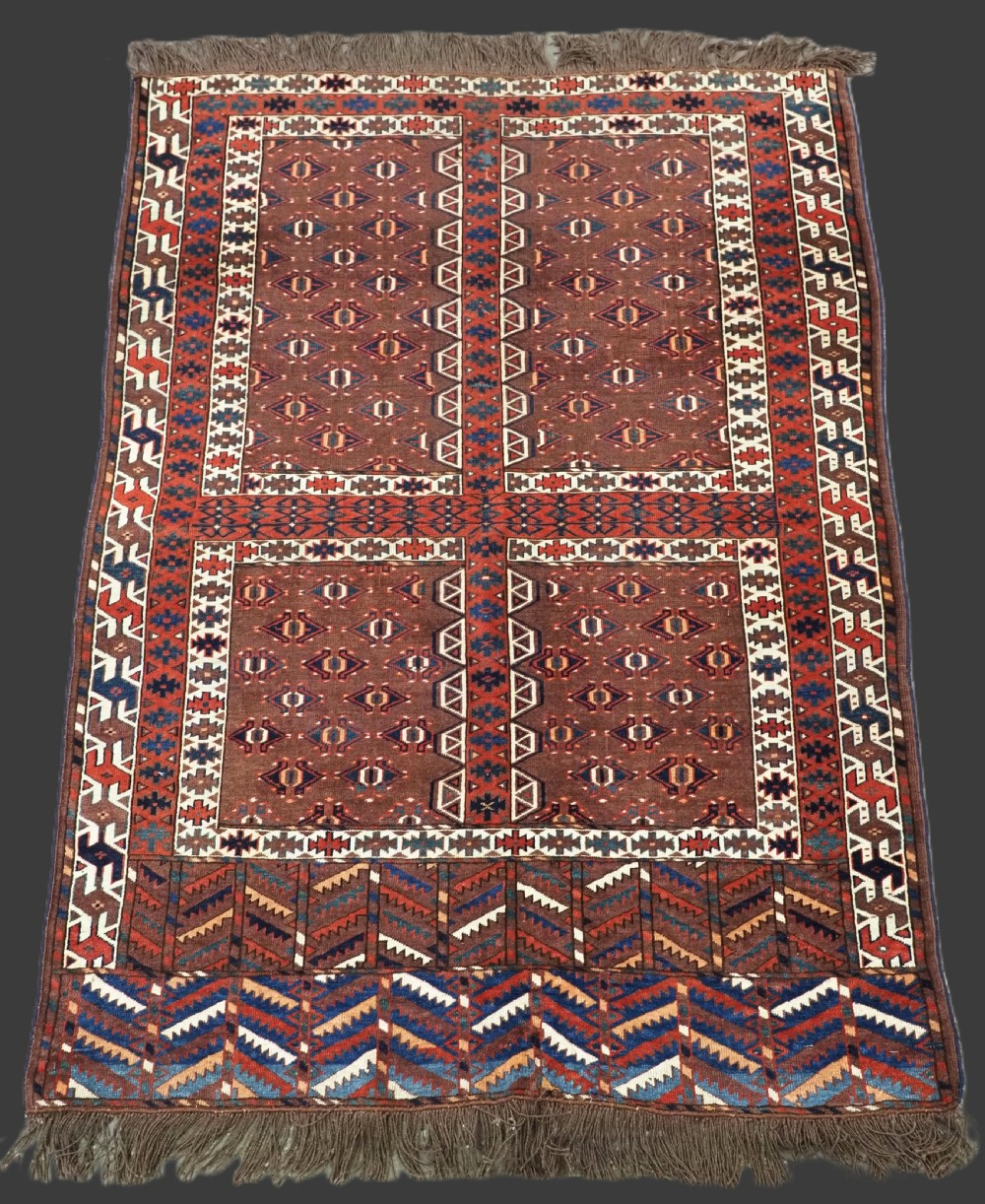 An antique late nineteenth-century Yomut Turkmen Ensi wool rug featuring a cruciform hatchli design in deep red-brown, navy blue, and ivory tones with a double tree elem skirt.