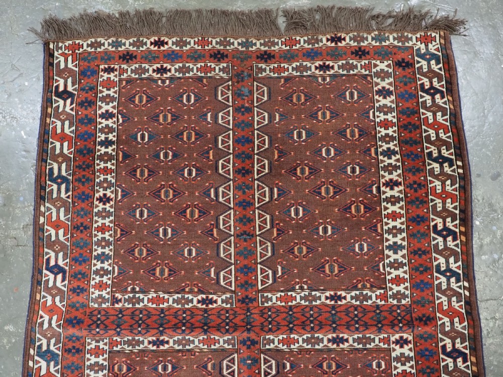 An antique late nineteenth-century Yomut Turkmen Ensi wool rug featuring a cruciform hatchli design in deep red-brown, navy blue, and ivory tones with a double tree elem skirt. View III