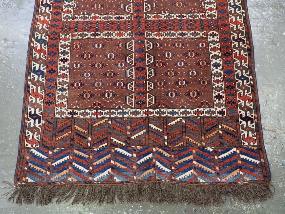 An antique late nineteenth-century Yomut Turkmen Ensi wool rug featuring a cruciform hatchli design in deep red-brown, navy blue, and ivory tones with a double tree elem skirt. View V
