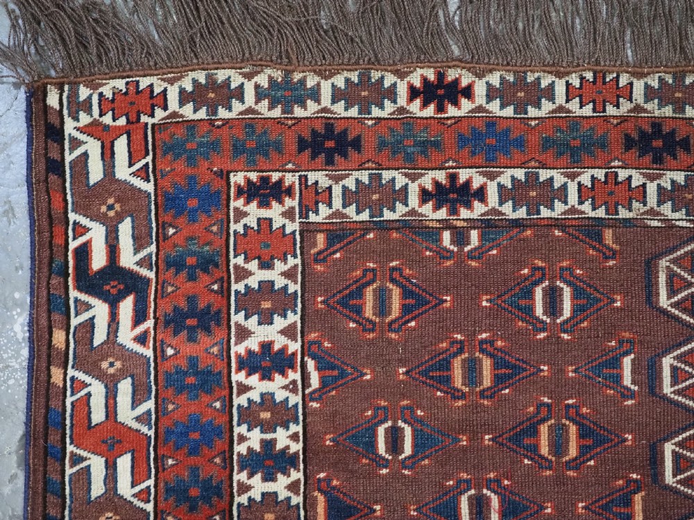 An antique late nineteenth-century Yomut Turkmen Ensi wool rug featuring a cruciform hatchli design in deep red-brown, navy blue, and ivory tones with a double tree elem skirt. View VI