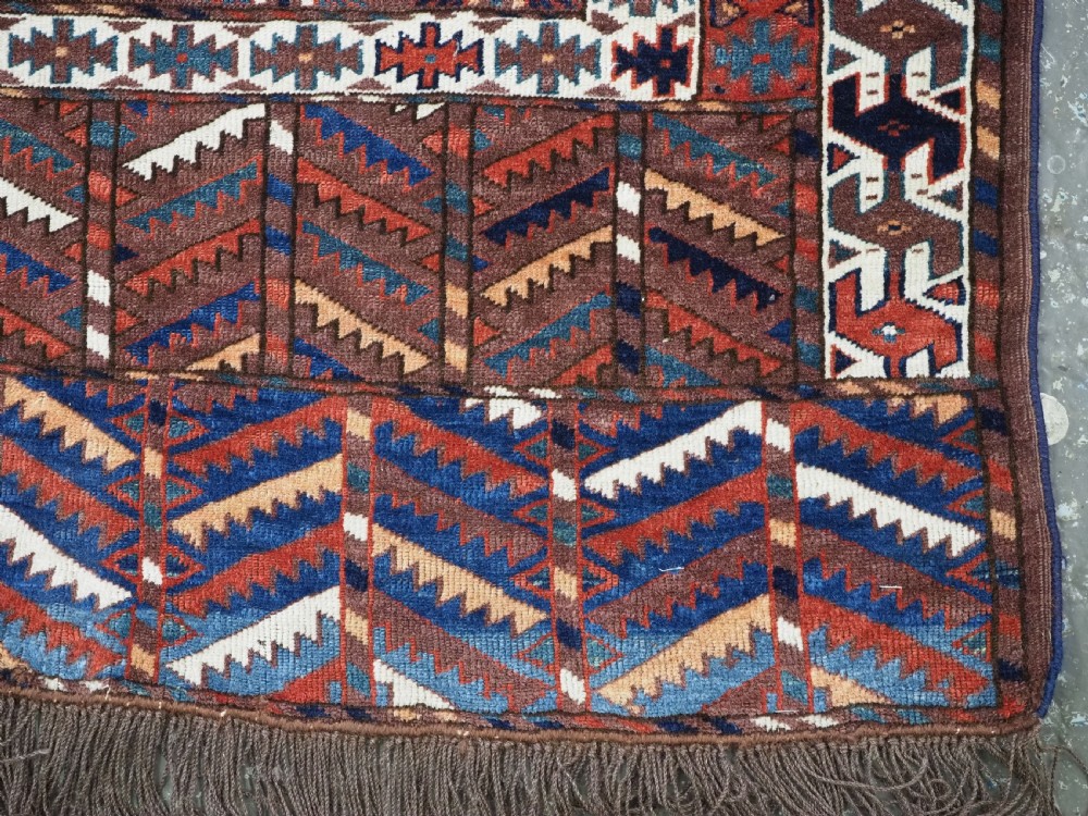 An antique late nineteenth-century Yomut Turkmen Ensi wool rug featuring a cruciform hatchli design in deep red-brown, navy blue, and ivory tones with a double tree elem skirt. View X