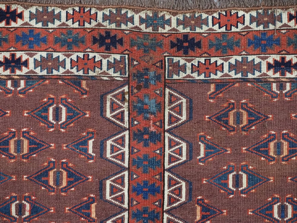 An antique late nineteenth-century Yomut Turkmen Ensi wool rug featuring a cruciform hatchli design in deep red-brown, navy blue, and ivory tones with a double tree elem skirt. View XI