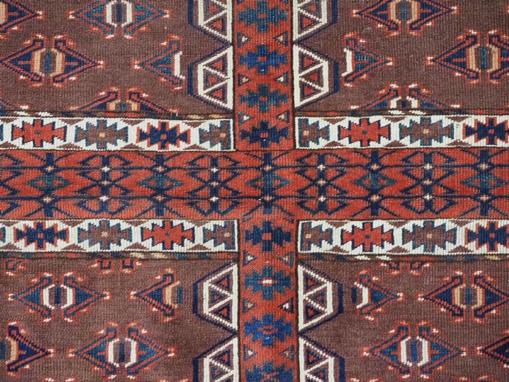 An antique late nineteenth-century Yomut Turkmen Ensi wool rug featuring a cruciform hatchli design in deep red-brown, navy blue, and ivory tones with a double tree elem skirt. View XII