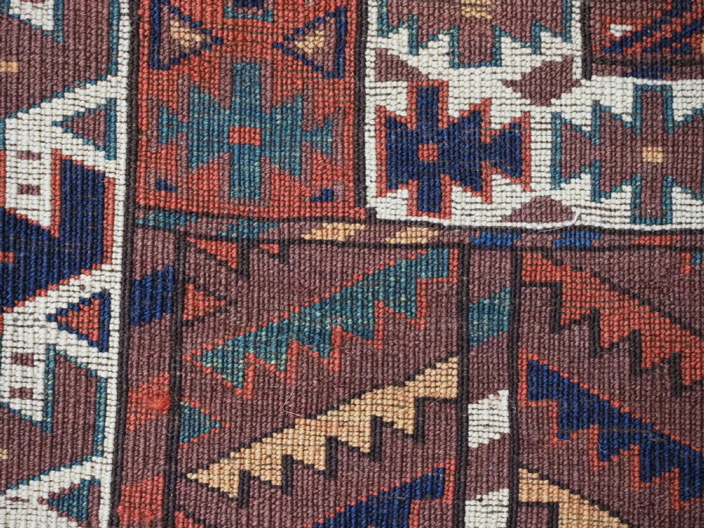 An antique late nineteenth-century Yomut Turkmen Ensi wool rug featuring a cruciform hatchli design in deep red-brown, navy blue, and ivory tones with a double tree elem skirt. View XV