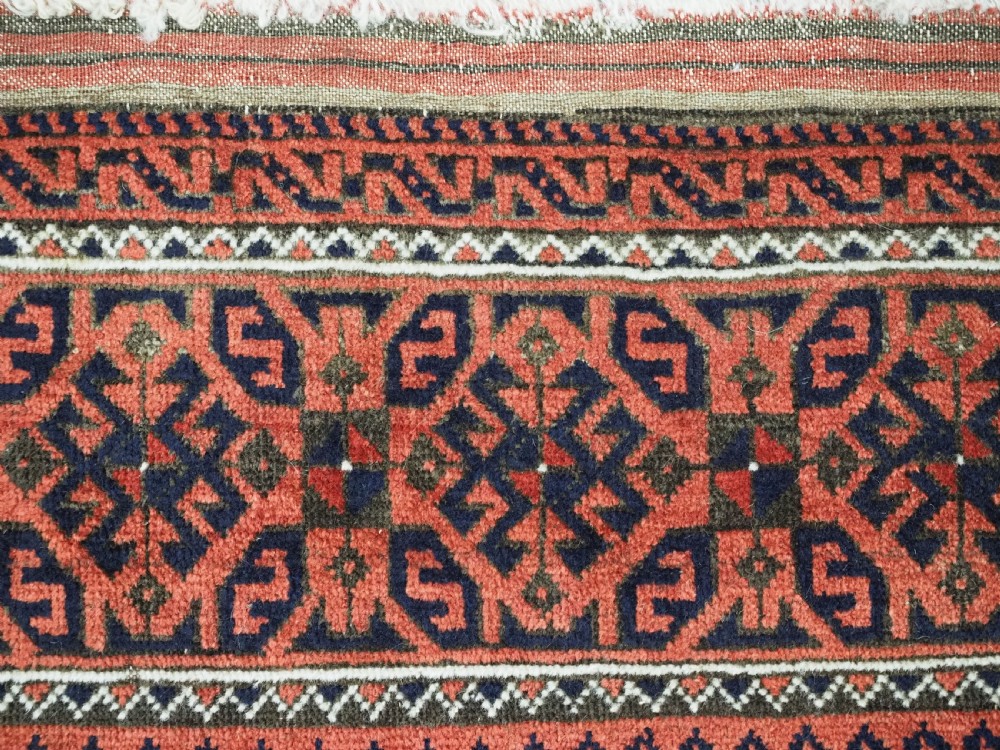 An antique hand-knotted wool rug featuring repeating geometric octagonal motifs in terracotta red and dark indigo blue. View VIII