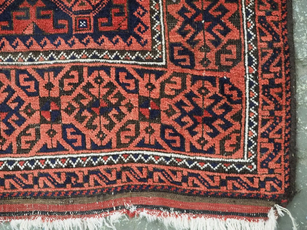 An antique hand-knotted wool rug featuring repeating geometric octagonal motifs in terracotta red and dark indigo blue. View XII
