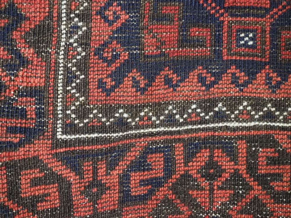 An antique hand-knotted wool rug featuring repeating geometric octagonal motifs in terracotta red and dark indigo blue. View XIII