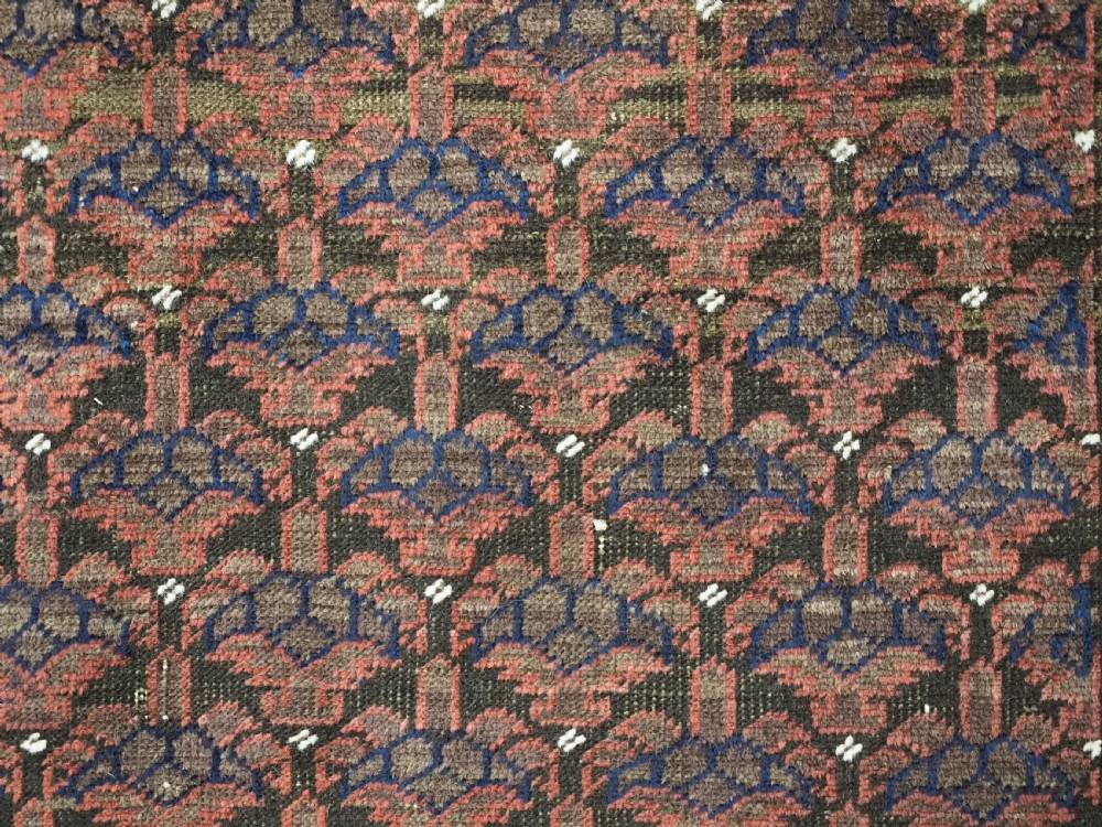 An antique hand-knotted Timuri Baluch wool rug featuring a dark red and brown field with a repeating small shrub design enclosed by geometric borders. View VII