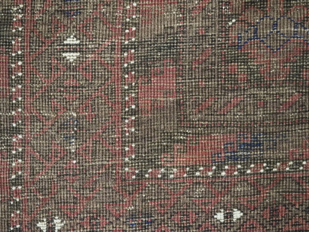 An antique hand-knotted Timuri Baluch wool rug featuring a dark red and brown field with a repeating small shrub design enclosed by geometric borders. View IX