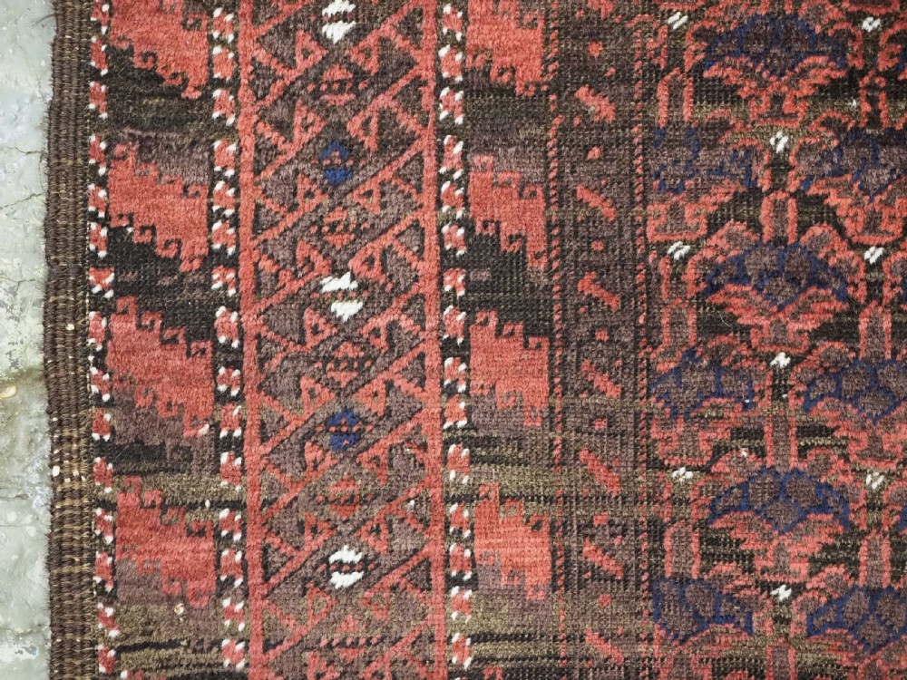 An antique hand-knotted Timuri Baluch wool rug featuring a dark red and brown field with a repeating small shrub design enclosed by geometric borders. View XII