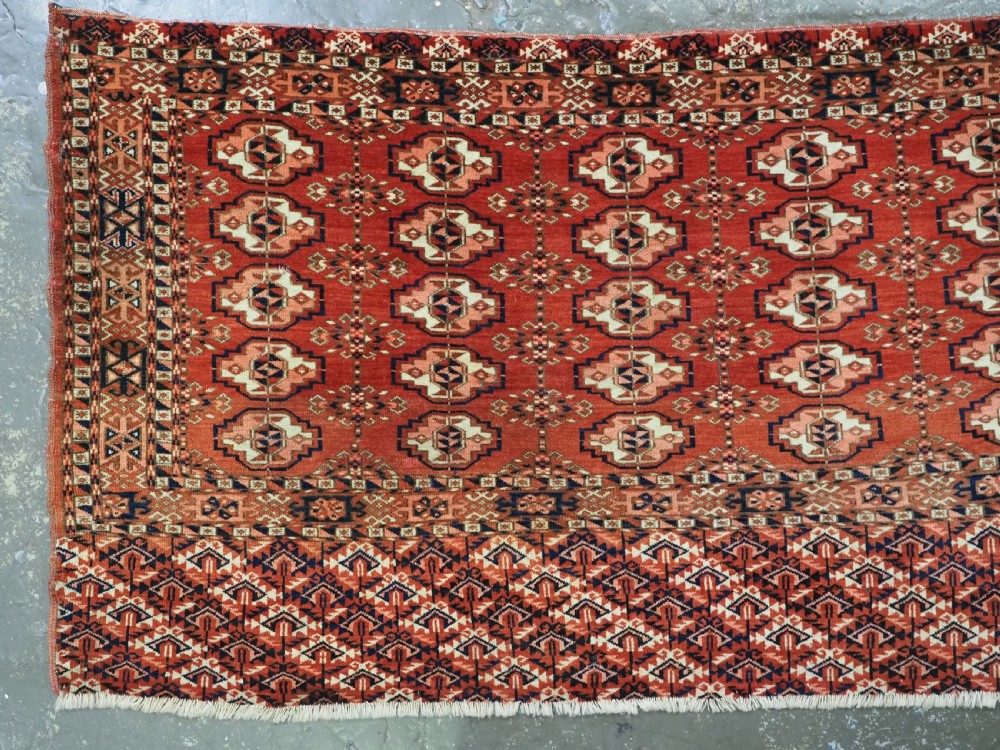 An antique Tekke Turkmen chuval woven textile face featuring thirty repeating octagonal guls on a deep red wool field with geometric borders and a decorated skirt. View II