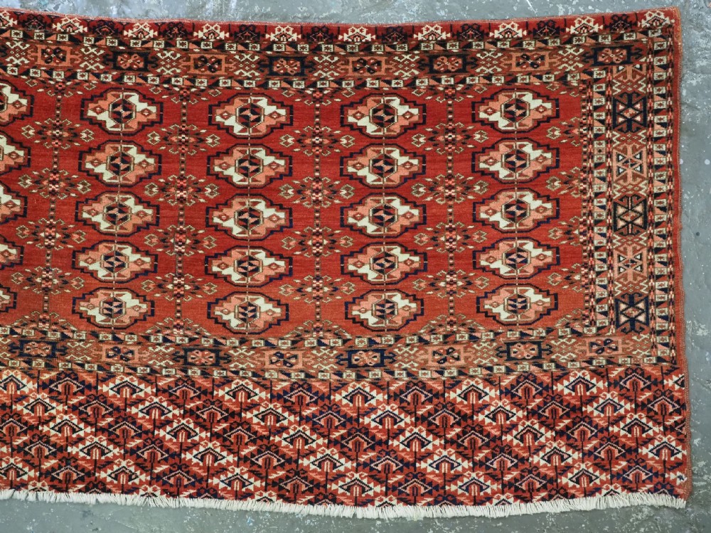 An antique Tekke Turkmen chuval woven textile face featuring thirty repeating octagonal guls on a deep red wool field with geometric borders and a decorated skirt. View III