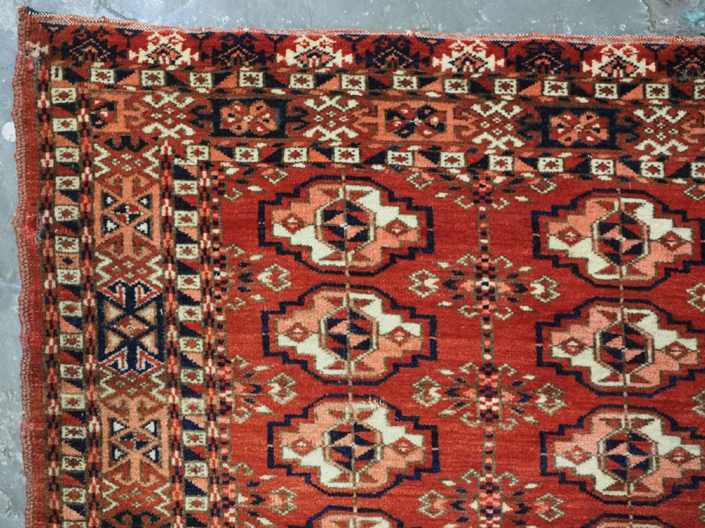 An antique Tekke Turkmen chuval woven textile face featuring thirty repeating octagonal guls on a deep red wool field with geometric borders and a decorated skirt. View IV