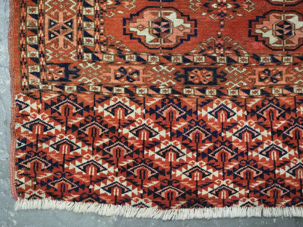 An antique Tekke Turkmen chuval woven textile face featuring thirty repeating octagonal guls on a deep red wool field with geometric borders and a decorated skirt. View V