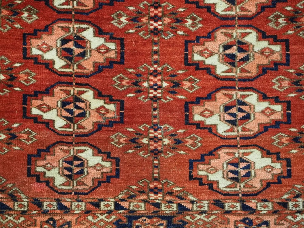 An antique Tekke Turkmen chuval woven textile face featuring thirty repeating octagonal guls on a deep red wool field with geometric borders and a decorated skirt. View VI