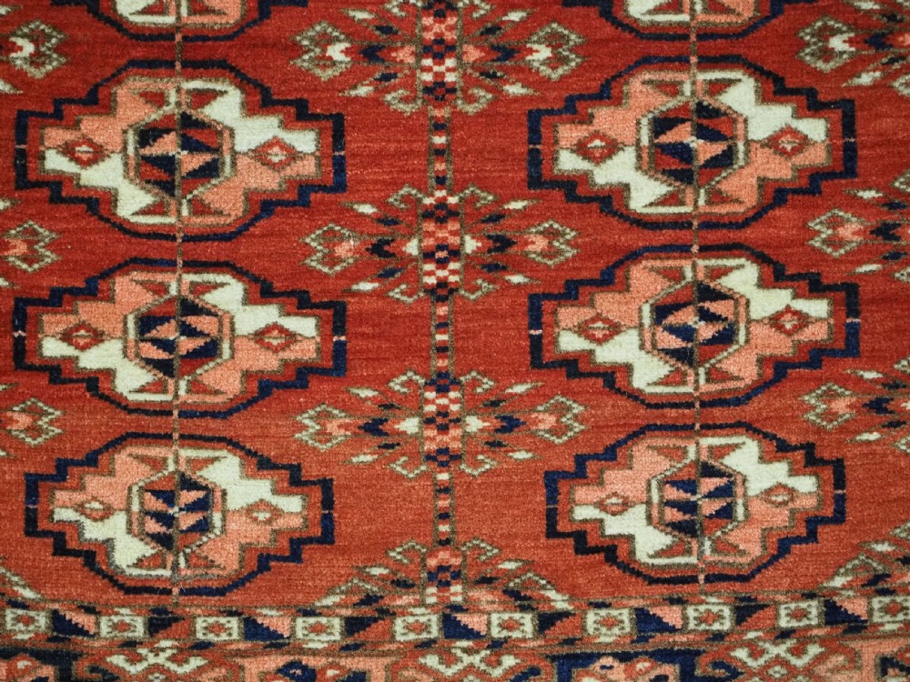 An antique Tekke Turkmen chuval woven textile face featuring thirty repeating octagonal guls on a deep red wool field with geometric borders and a decorated skirt. View VII