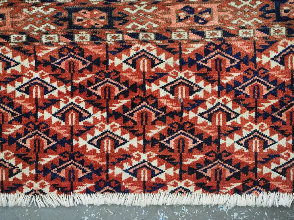 An antique Tekke Turkmen chuval woven textile face featuring thirty repeating octagonal guls on a deep red wool field with geometric borders and a decorated skirt. View VIII